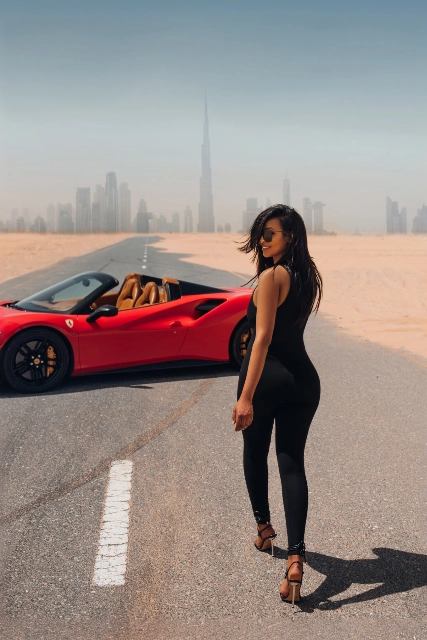 A woman standing next to a red sports car.
