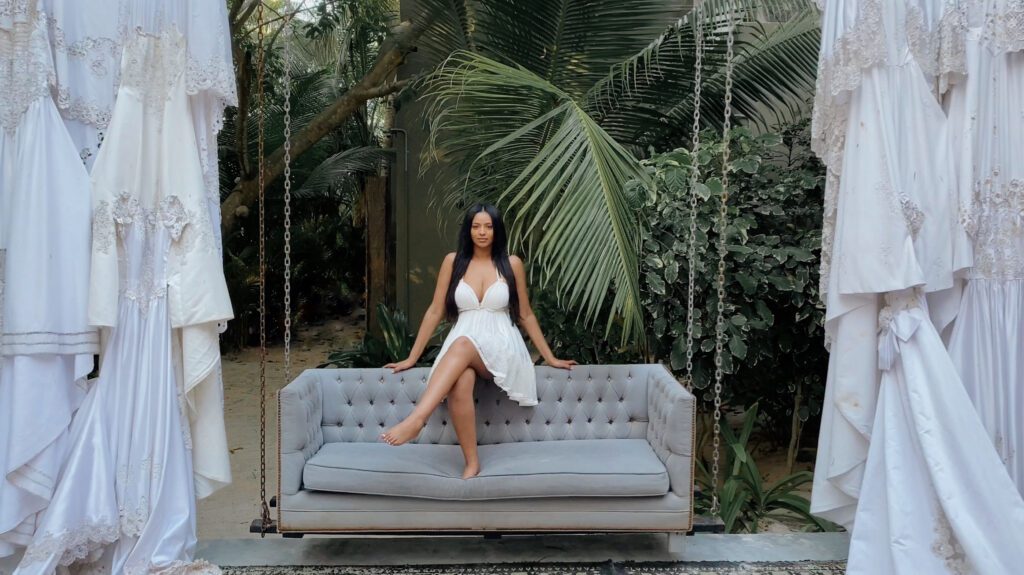 A woman in white dress sitting on a couch.