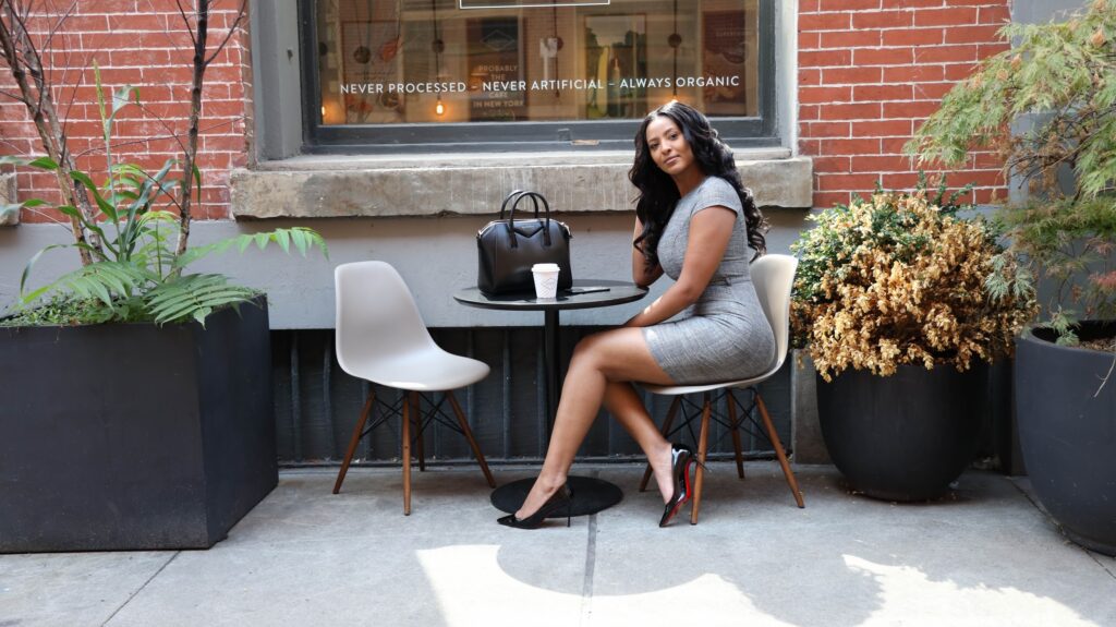 A woman sitting at an outdoor table with her purse.