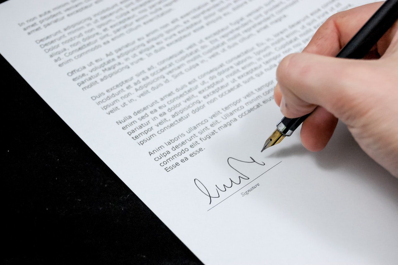 A person signing a document with a pen.