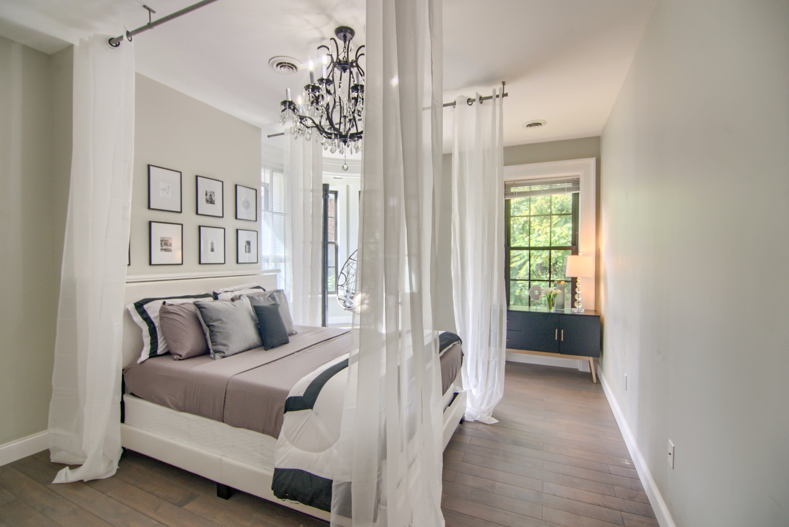 A bedroom with white walls and wooden floors.