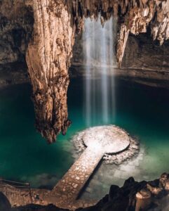 A large waterfall in the middle of an underground pool.
