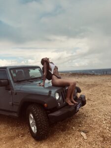 A woman sitting on the hood of a jeep.
