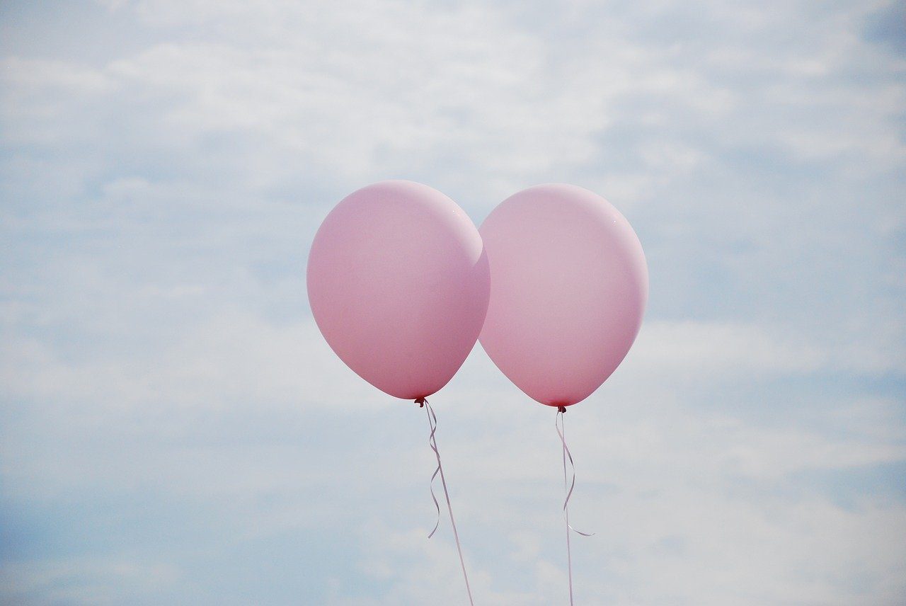 Two pink balloons floating in the sky