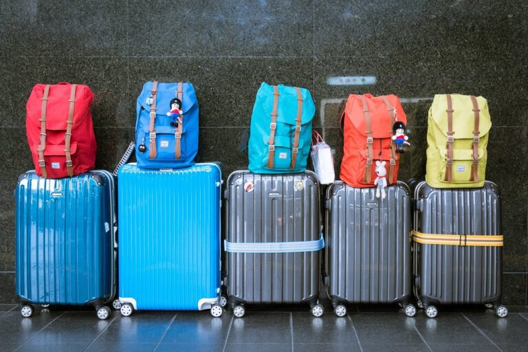 A row of suitcases and backpacks sitting on the floor.