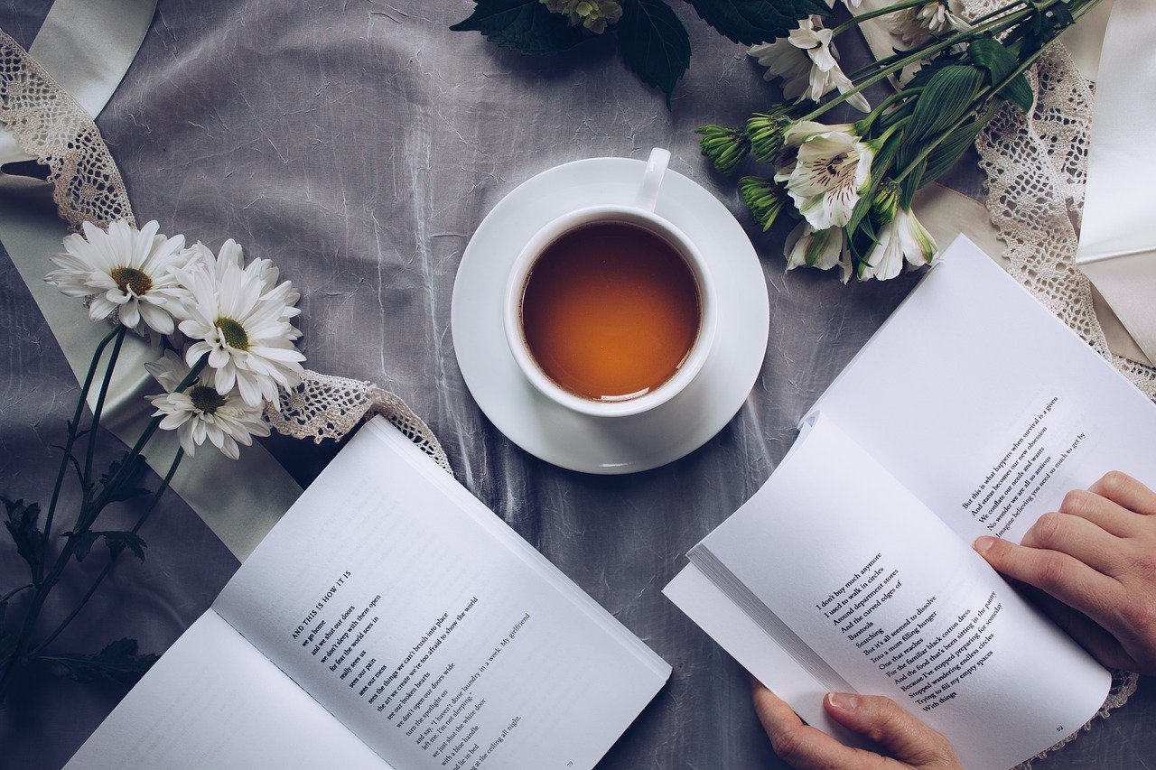 A person is reading a book while drinking tea.