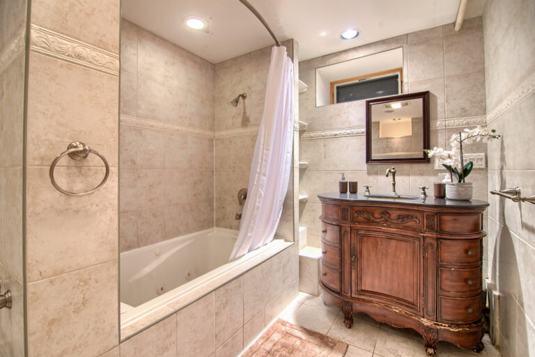 A bathroom with a tub, sink and mirror.