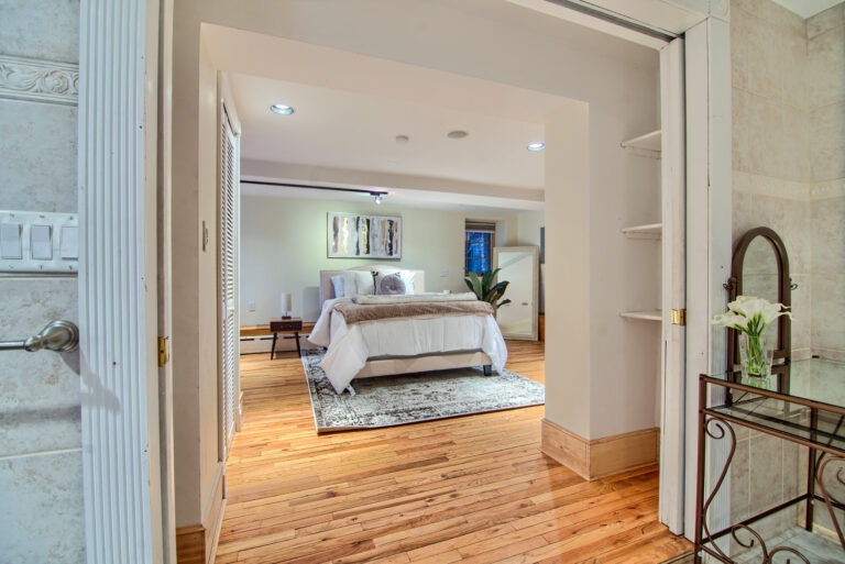 A bedroom with hardwood floors and white walls.