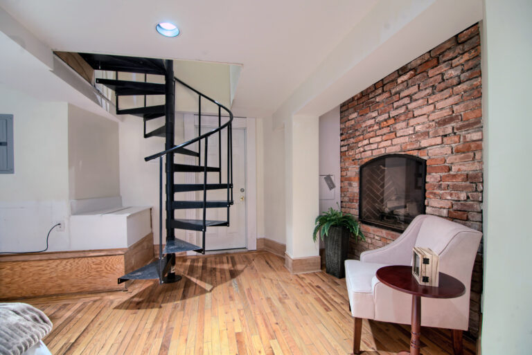 A room with a fire place and stairs leading to the top floor.