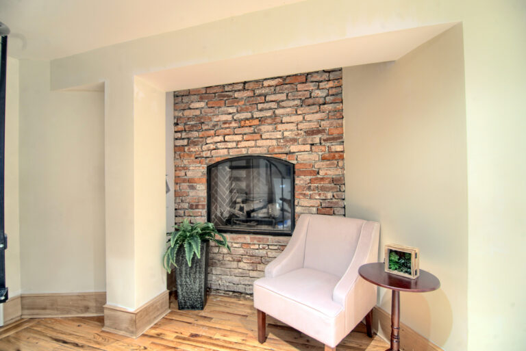 A chair and table in front of a fireplace.