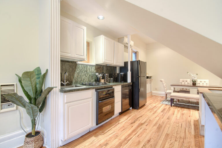 A kitchen with white cabinets and black appliances.