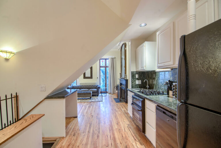 A kitchen with white cabinets and wood floors