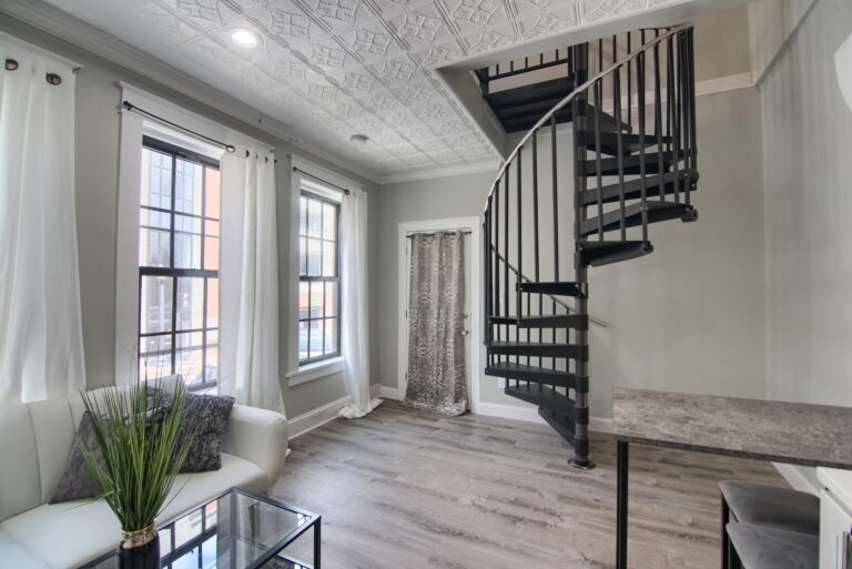 A living room with a spiral staircase and a glass table