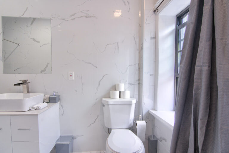 A bathroom with white marble walls and floors.