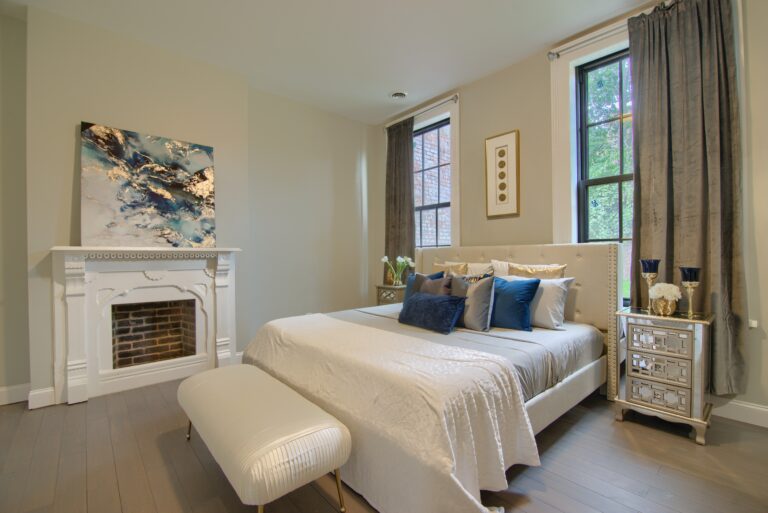 A bedroom with a fireplace and white furniture.