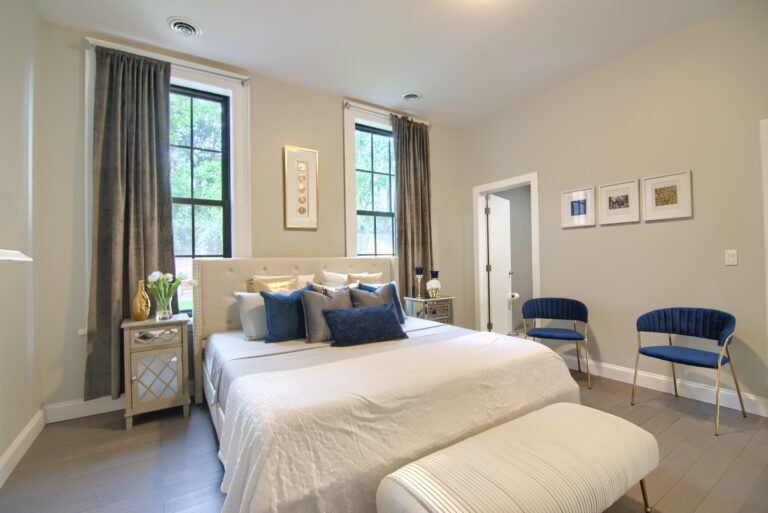 A bedroom with a large bed and two windows.