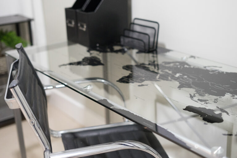 A glass table with black chairs and a map of the world on it.