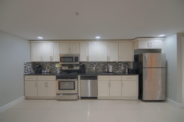 A kitchen with white cabinets and black counter tops.