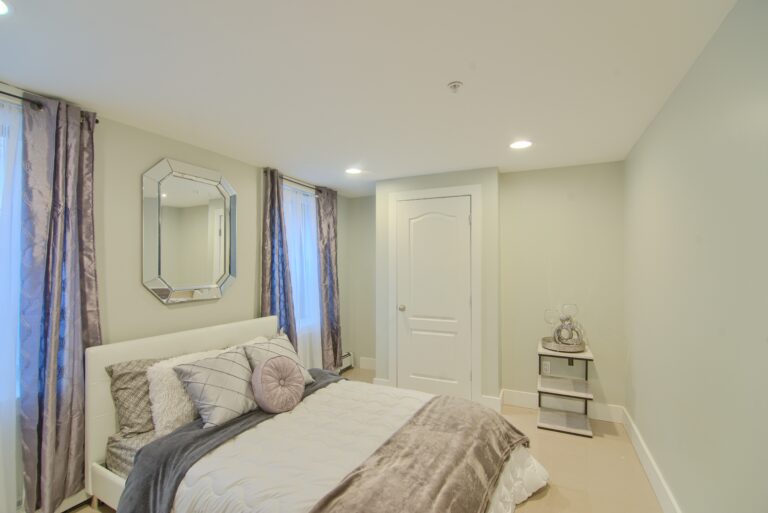 A bedroom with white walls and beige furniture.