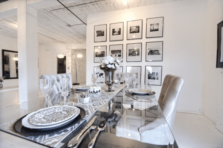 A dining room table with chairs and pictures on the wall.