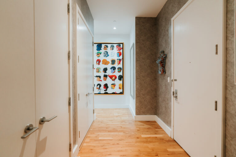 A hallway with two doors and a wall hanging