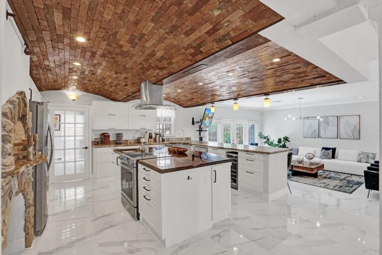 A large kitchen with white cabinets and wooden ceiling.