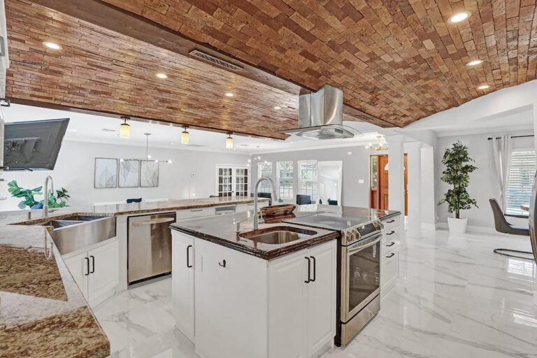 A large kitchen with white cabinets and marble floors.