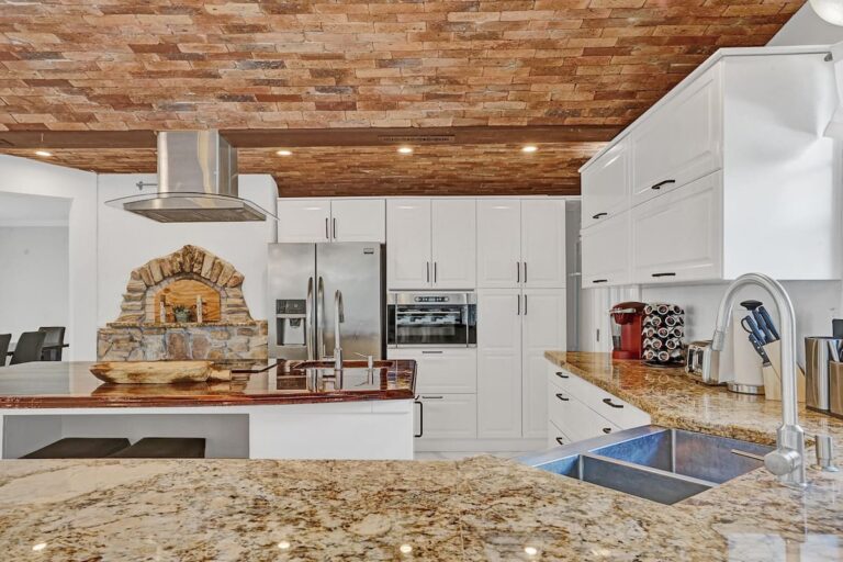 A kitchen with white cabinets and granite counter tops.