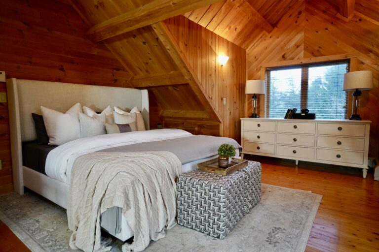 A bedroom with wood paneled walls and a white bed.