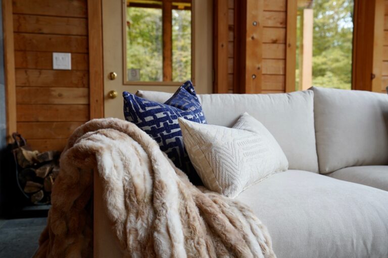 A white couch with pillows and blankets on it.